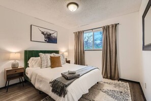 A bedroom with a bed, a nightstand, a lamp, a framed picture, and a window with curtains. - Stylish Townhouse Retreat - 15 min to DT (Westminster)