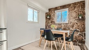 A dining area with a stone wall, a wooden table, and black chairs.