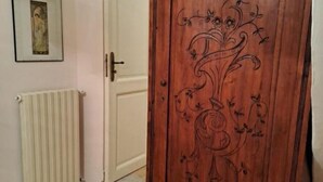 A wooden door with floral carvings, a white radiator, and a framed picture on the wall. - Cilento Antico Holiday Homes a few km from the sea (Stella Cilento)