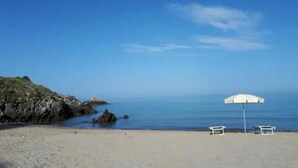 A beach with a white umbrella and two chairs. - Cilento Antico Holiday Homes a few km from the sea (Stella Cilento)