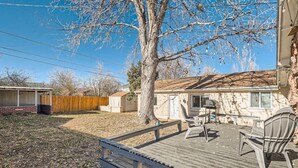A backyard with a wooden deck, a barbecue grill, and a covered patio area.