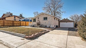 A two-story house with a garage, a fenced yard, and a clear blue sky.
