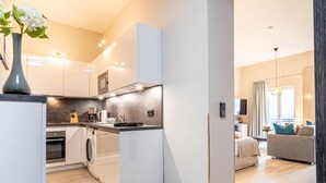 A modern kitchen with integrated appliances, a dining area with a sofa, and a view of the outdoors. - Appartement Himmelblau mit Blick auf Bodden und Ostsee im Ostseebad Wustrow (Wustrow)