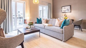 A modern living room with a grey sofa, a coffee table, and a dining area with a chair and table. - Appartement Himmelblau mit Blick auf Bodden und Ostsee im Ostseebad Wustrow (Wustrow)