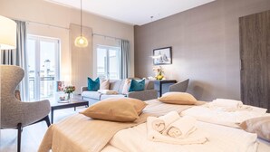 A hotel room with a large bed, a sofa, a coffee table, and a view of the city through the windows. - Appartement Himmelblau mit Blick auf Bodden und Ostsee im Ostseebad Wustrow (Wustrow)
