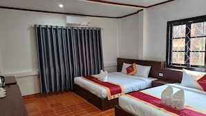 Een hotelkamer met twee bedden, een houten vloer, een raam met uitzicht en een gordijn.