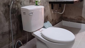Een badkamer met een toilet, een douche, een wastafel en een spiegel.