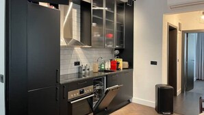A modern kitchen with black cabinetry, a stainless steel oven, and a built-in dishwasher. - NEW SOHO 13 - TOP Center, black & white (Sofia)