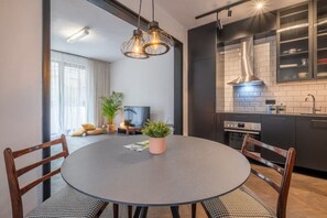 Moderni keittiö, jossa on tummat kaapit, sisäänrakennettu uuni ja ruostumattomasta teräksestä valmistettu pesuallas.