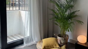 A room with a large window, sheer curtains, a potted plant, and a checkered floor. - NEW SOHO 13 - TOP Center, black & white (Sofia)