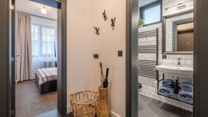 A hotel room with a bed, a wicker basket, and a wall-mounted towel rack. - NEW SOHO 13 - TOP Center, black & white (Sofia)
