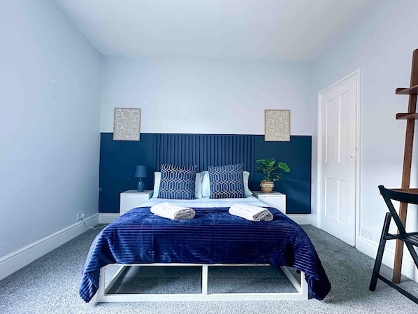 A bedroom with a bed, bedside tables, a chair, and a door.