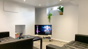 A modern living room with a flat-screen TV, leather sofas, a coffee table, and a small plant. - Spacious & stylish 3-bed home in Centre of Canterbury (Canterbury)