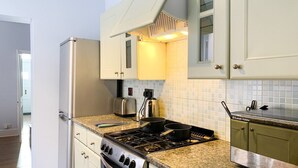 A compact kitchen with a stove, toaster, and refrigerator. - Spacious & stylish 3-bed home in Centre of Canterbury (Canterbury)