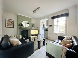 A living room with two sofas, a coffee table, a fireplace, and a television.