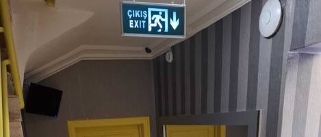 Un pasillo con una puerta amarilla marcada con el número 2, un muro espejado y un cartel que indica 'ÇIKIŞ EXIT'.