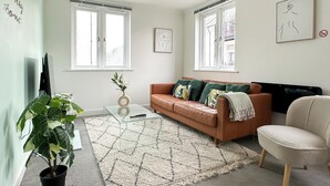 A living room with a sofa, a chair, a coffee table, and a potted plant.