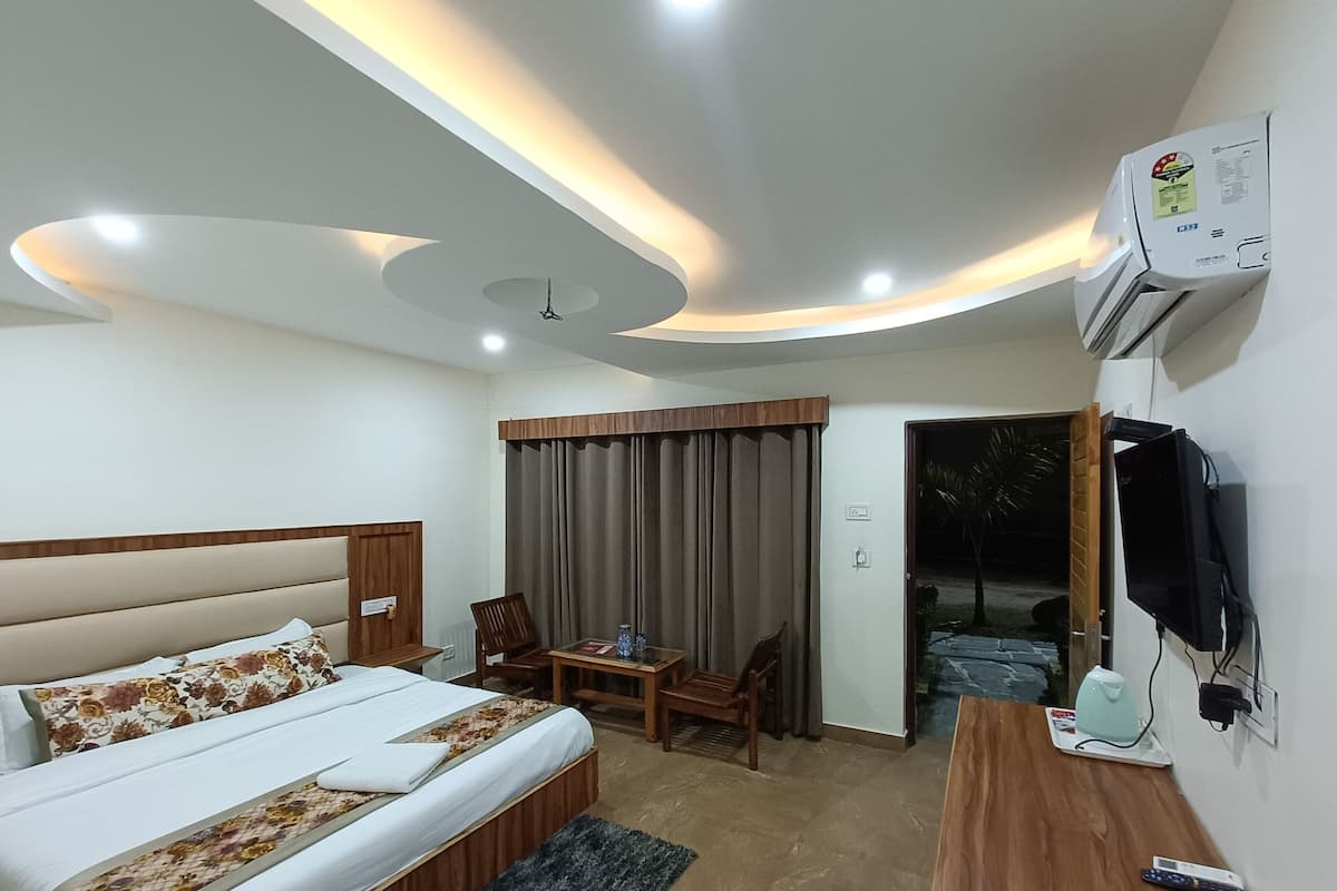 A hotel room with a bed, a desk, a chair, a table, and a TV.