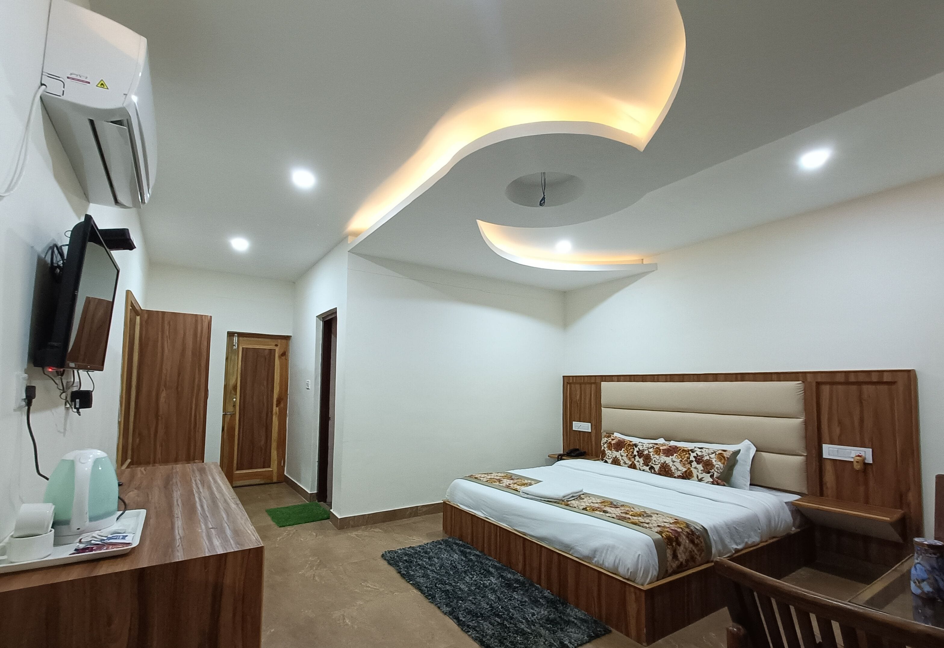 Un dormitorio moderno con cama, mesitas de noche, escritorio y televisión.