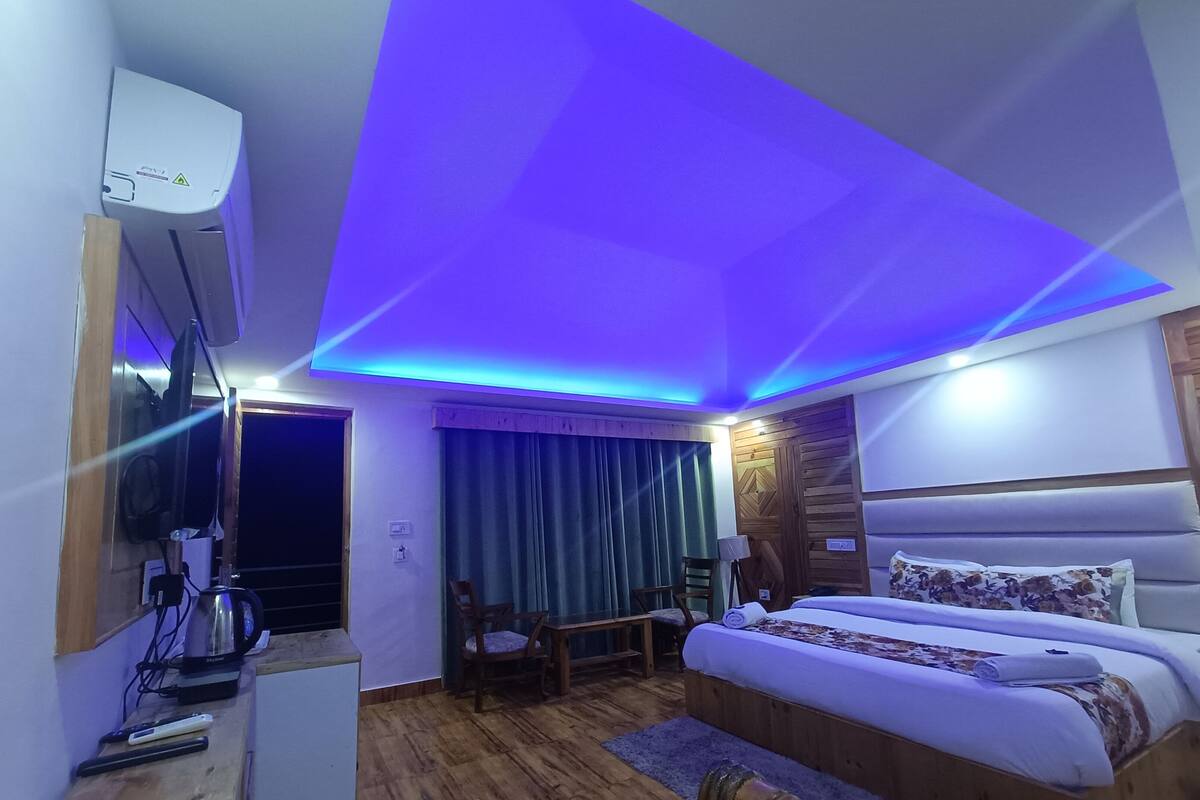 A hotel room with a bed, a desk, a chair, a coffee maker, and a TV.