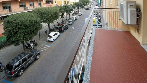 A street view with parked cars, trees, and multi-story buildings. - Europa 29 Trilocale Manhattan (Loano)