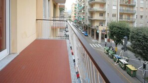 A residential building with balconies, a street with parked cars, and a visible trash bin. - Europa 29 Trilocale Manhattan (Loano)