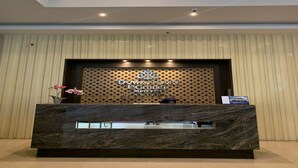 A reception desk with a dark marble top and a sign above it. - Capital O 93636 La Grande Apartment By UJM (Bandung)