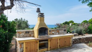 An outdoor kitchen with stone walls and wooden cabinets, overlooking a scenic landscape. - Villa Donna Eleonora - Alloggio Stella Marina (Morciano di Leuca)