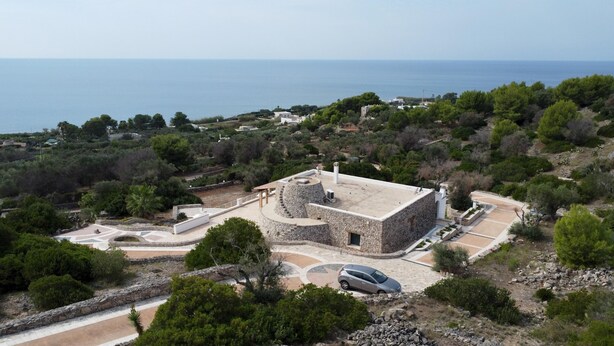 A stone building with a circular courtyard, surrounded by greenery and overlooking a coastal area. - Villa Donna Eleonora - Alloggio Stella Marina (Morciano di Leuca)