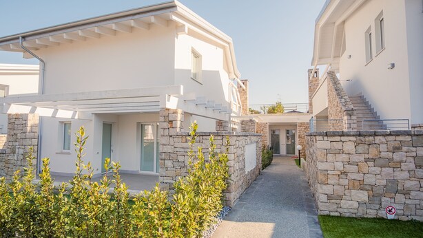 A modern villa with a stone facade, a covered outdoor area, and a visible staircase leading to an upper level. - Il Vento del Sud - Italian Homing (Padenghe sul Garda)