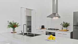 A modern kitchen with white cabinetry, a stainless steel sink, and a gas stove.