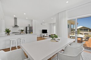 A modern kitchen with white cabinetry, a central island, and a dining area with white chairs.