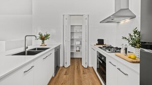 A modern kitchen with white cabinetry, a built-in oven, and a stainless steel range hood.