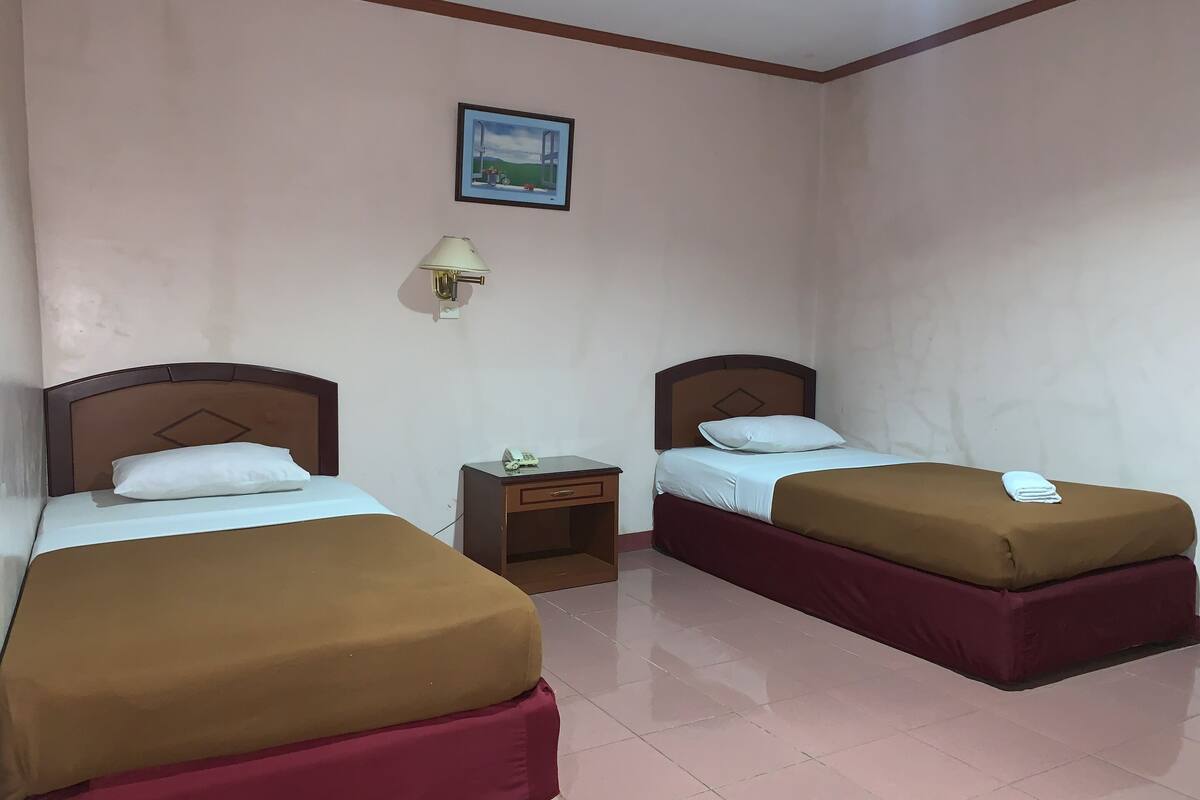 Une chambre d’hôtel avec deux lits, une table de chevet, une lampe et un tableau au mur.