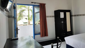 A room with a bed, a desk, a wardrobe, a door with a curtain, and an air conditioning unit. - Hotel O Pondok Baruga 777 Near Sarewo Musik Studio Kendari (Kendari)