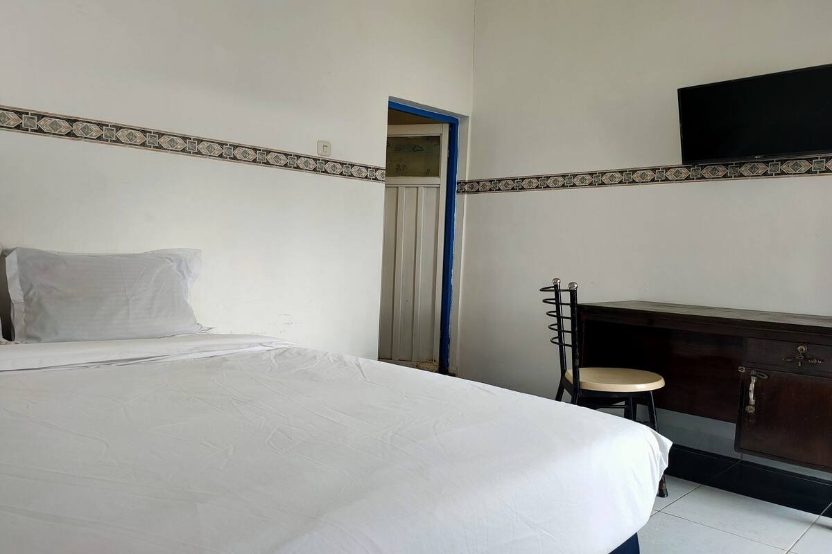 Une chambre à coucher avec un lit, un bureau, une chaise et un téléviseur fixé au mur.