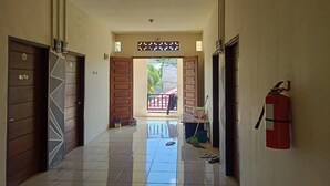 A hallway with wooden doors, a fire extinguisher, and a mop on the floor. - Hotel O Pondok Baruga 777 Near Sarewo Musik Studio Kendari (Kendari)