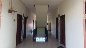 A hallway with doors on both sides, a tiled floor, and a ceiling light fixture. - Hotel O Pondok Baruga 777 Near Sarewo Musik Studio Kendari (Kendari)