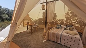 Ein Zelt mit einem Bett, einem Tisch und einem Stuhl im Inneren.