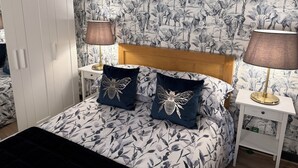 A bedroom with a bed, two nightstands, a wooden headboard, and a wardrobe. - Herbert George Apartment Hotel  (Clairac)