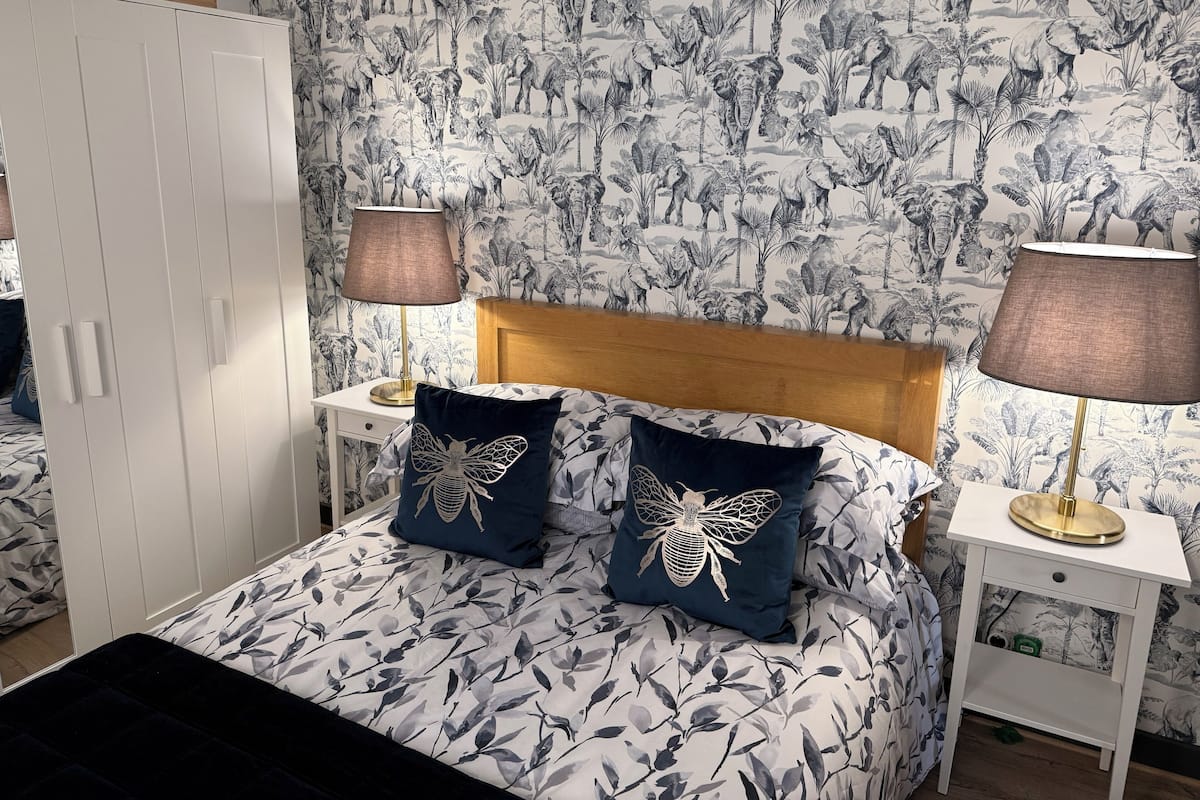 A bedroom with a bed, two nightstands, a wooden headboard, and a wardrobe.