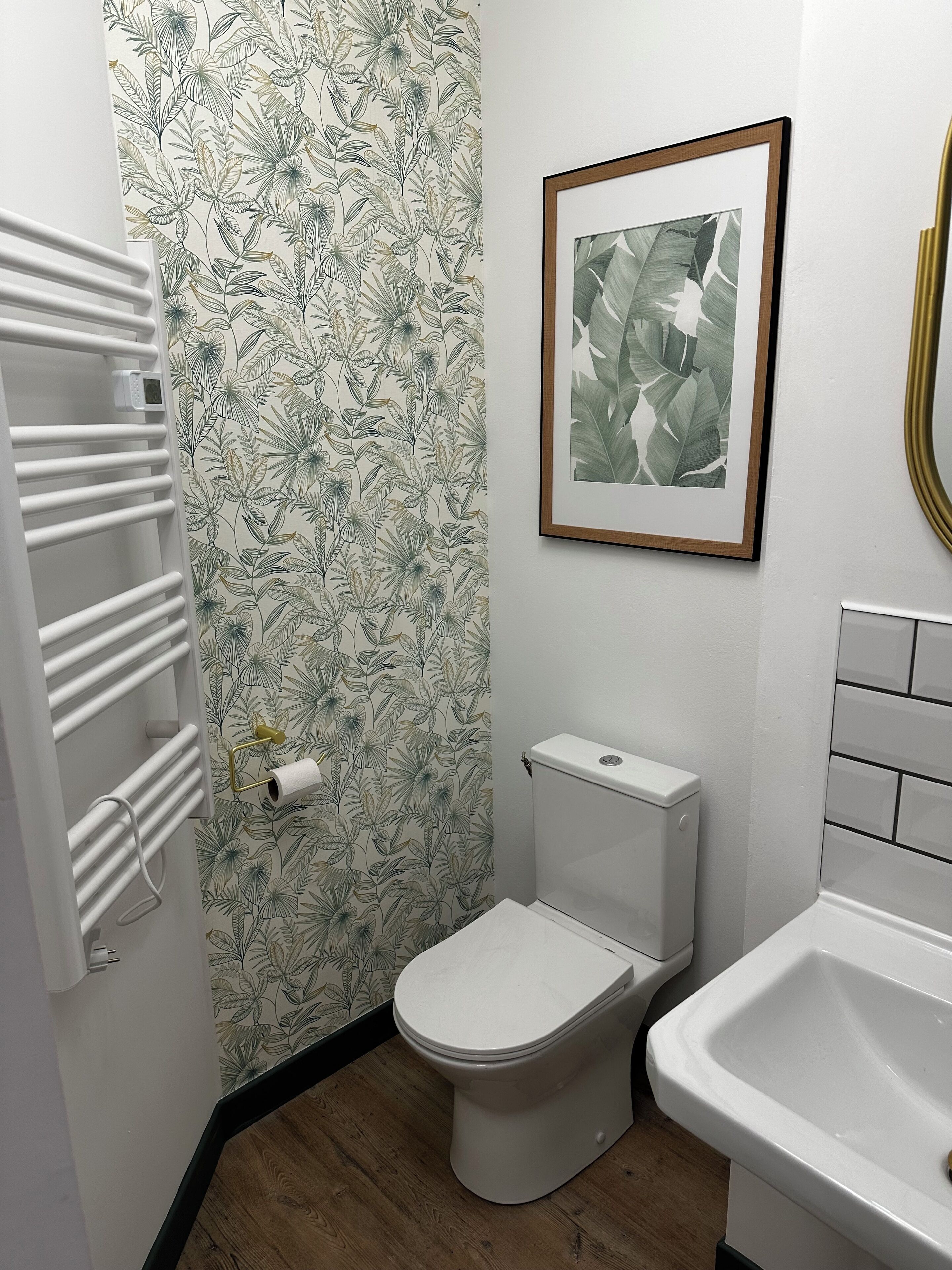 Un baño con inodoro, lavamanos, toallero y un cuadro enmarcado en la pared.