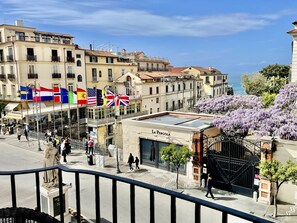 Un hôtel arborant plusieurs drapeaux, orné d’une statue et offrant une vue sur la mer.