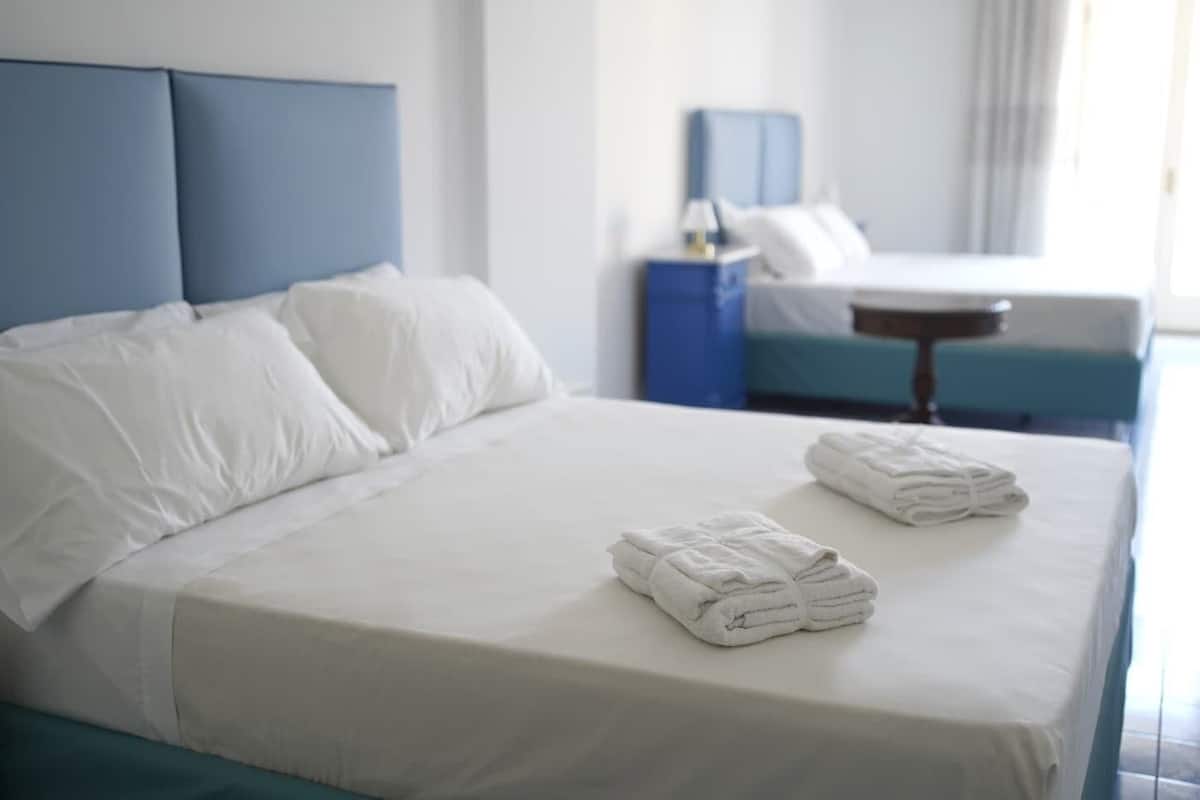 Una cama bien hecha con sábanas blancas y dos toallas dobladas sobre la cama.