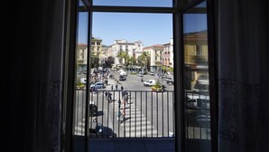 Blick aus einem Fenster auf eine belebte Straße mit Gebäuden und Palmen.