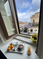 A breakfast tray with pastries, oranges, and a glass of orange juice on a windowsill.