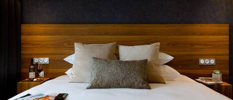 A neatly made bed with a wooden headboard, two bedside tables with lamps, and a magazine on the bed.
