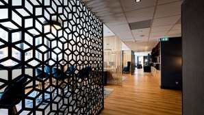 Un intérieur moderne avec un mur orné d’un motif géométrique, un plancher en bois et des chaises bleues disposées en rangée.