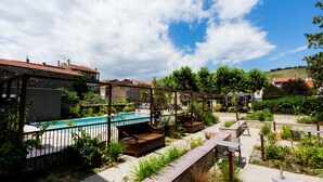 Un espace aménagé au bord de la piscine, avec des sièges d’extérieur, une piscine et une vue sur les bâtiments environnants.