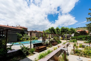 Zona junto a la piscina con mobiliario exterior, una piscina y vistas de edificios circundantes.